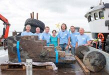 Members of the licensee and archaeological teams with the recovered gun carriage from the ship © Historic England