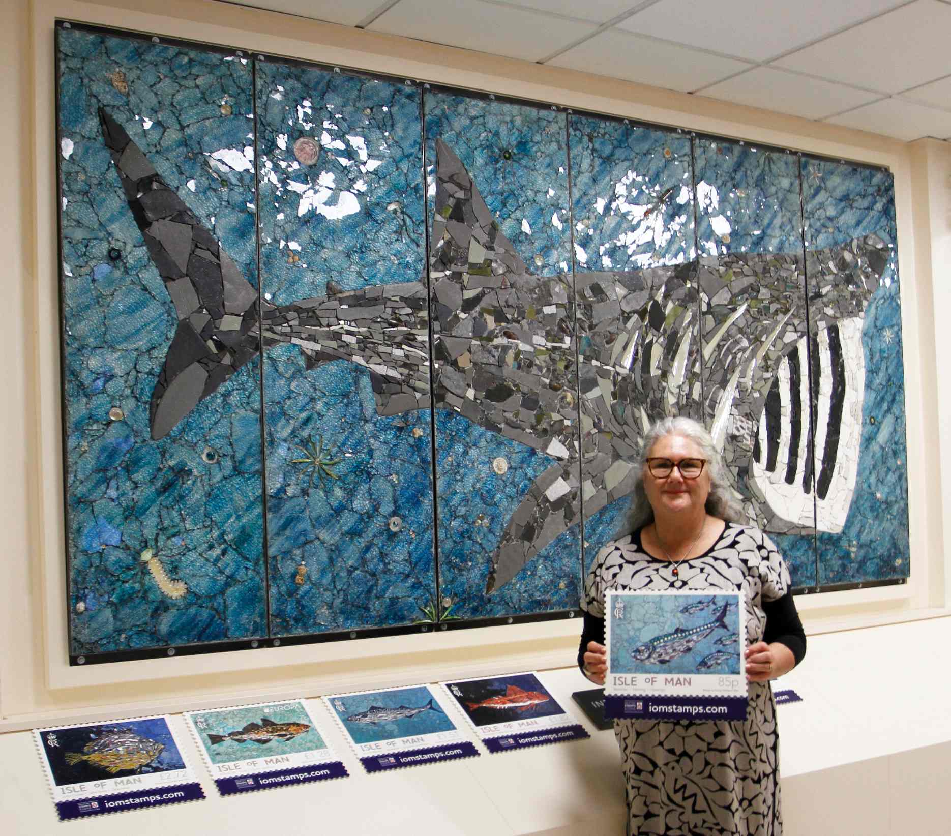 Kimmy McHarrie with the set of stamps and her new basking shark mural (IoM Post Office)